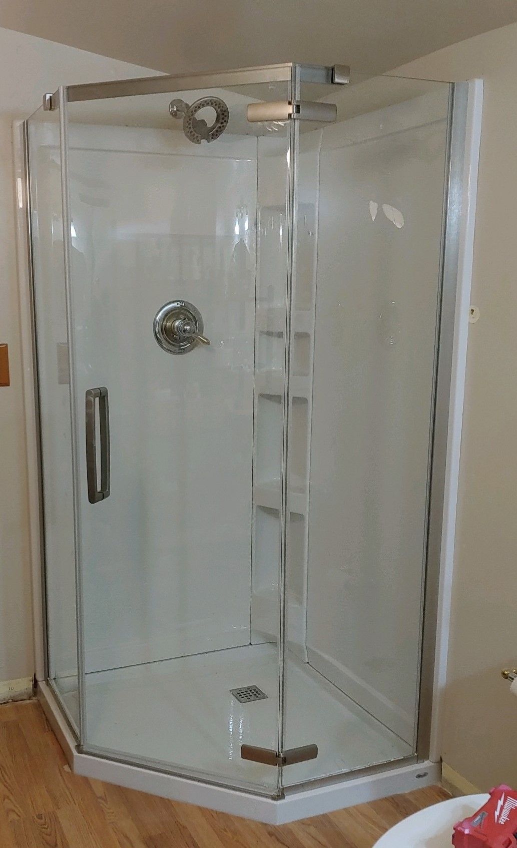 White and clear glass corner shower with chrome fixtures in a bathroom.