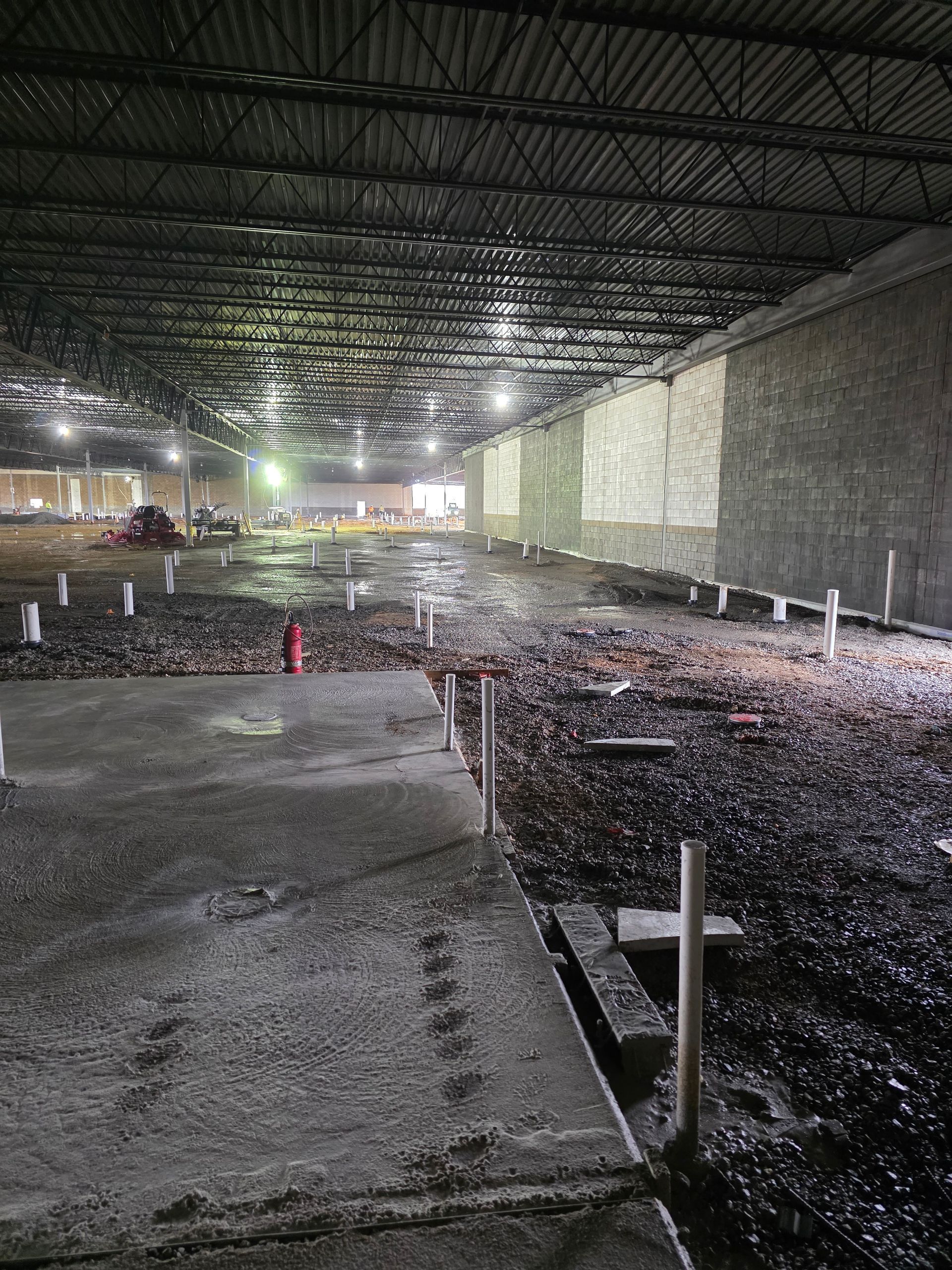 Interior view of a large, damaged building. Debris and dark residue cover the floor.  Walls are visible with some light.