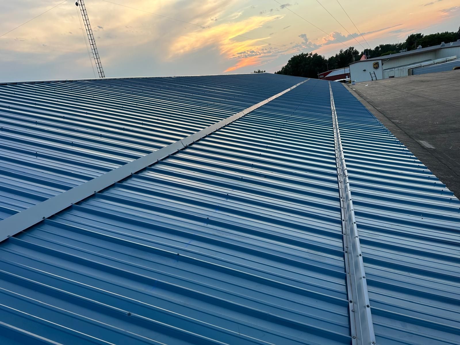 Blue corrugated metal roof with white trim, against a dusky sky.