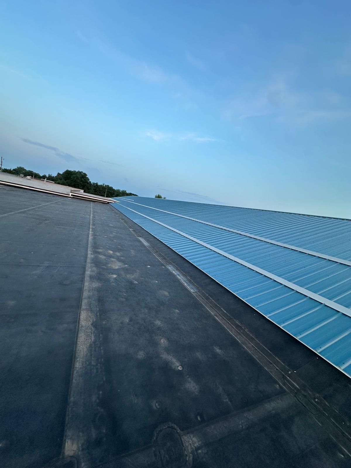 Solar panels on a dark roof under a blue sky.