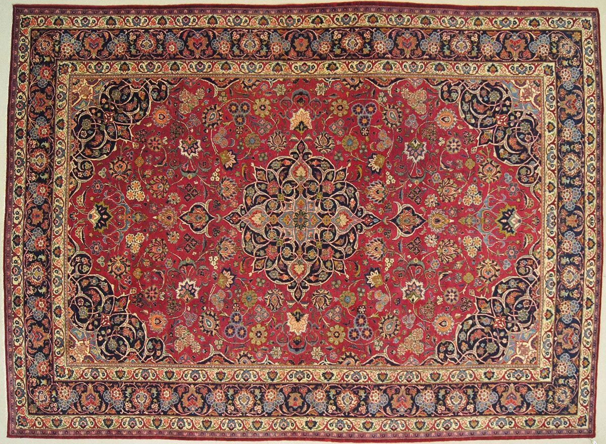 Red Persian rug with intricate floral designs, dark blue border, and central medallion