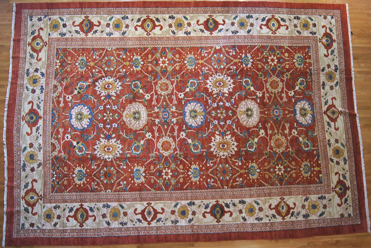 Red and ivory rectangular rug with floral and geometric patterns on hardwood floor
