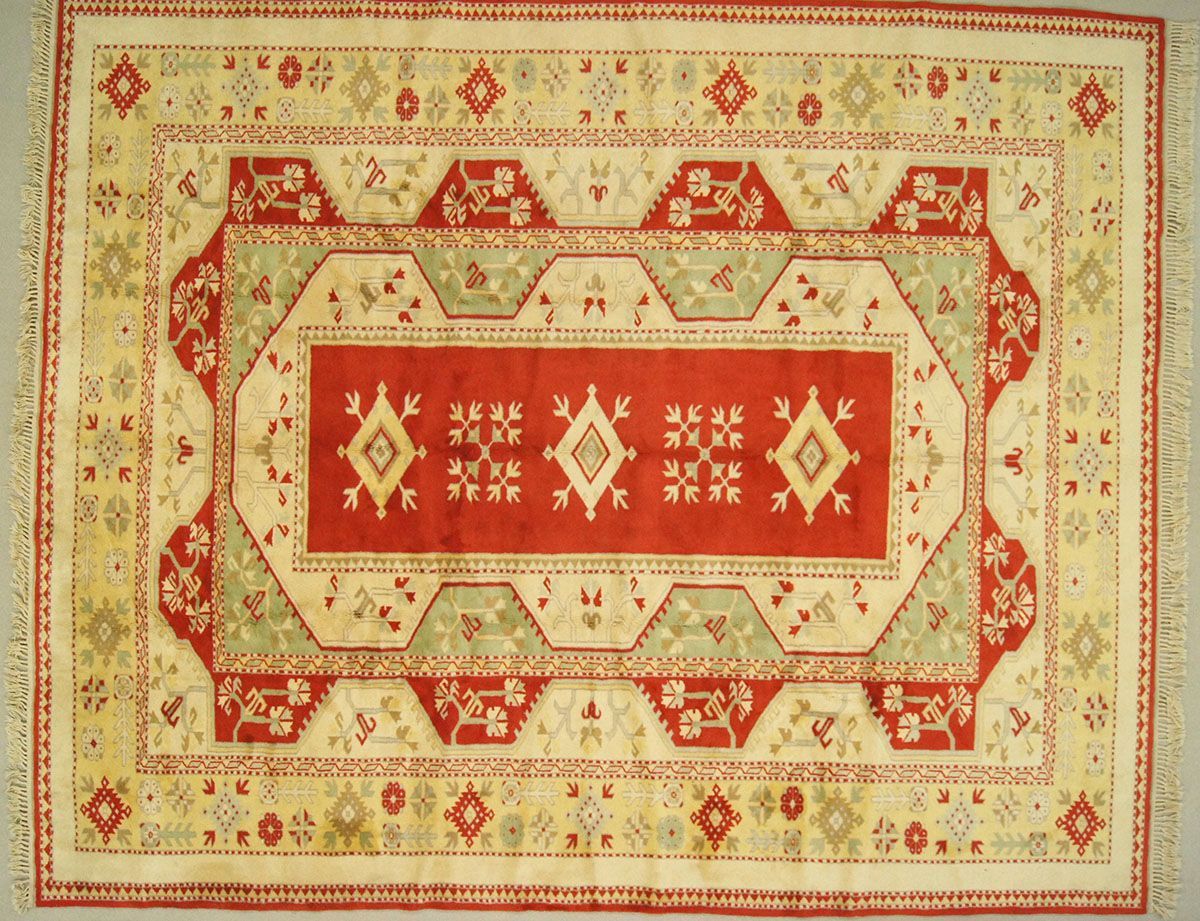 Red, beige, and green patterned rug with a central rectangular design and border