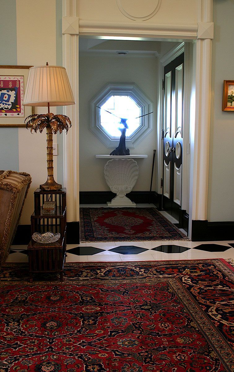 Elegant entryway with red rugs, black and white checkered floor, ornate lamp, and octagon window