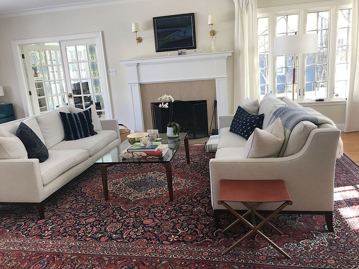 Living room with white sofas, a patterned rug, a fireplace, and a glass coffee table