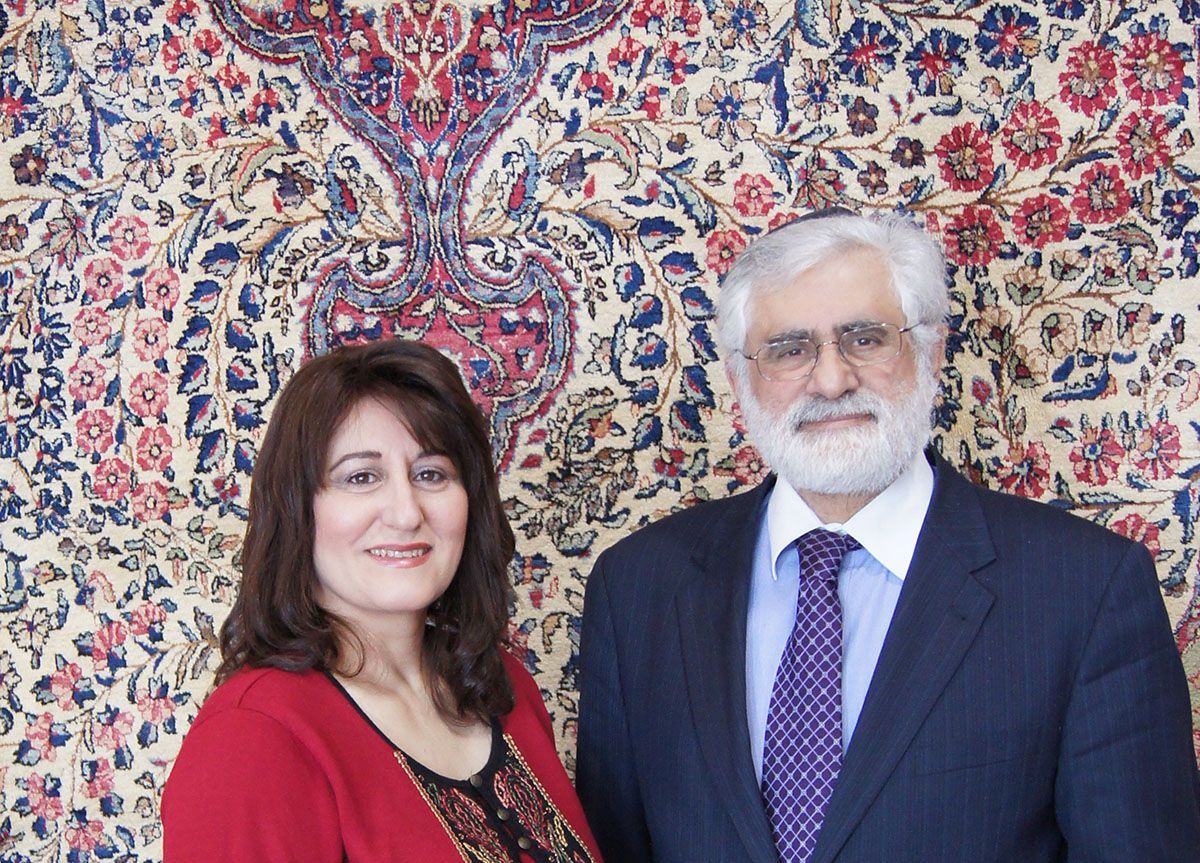 A man and woman stand before a patterned rug