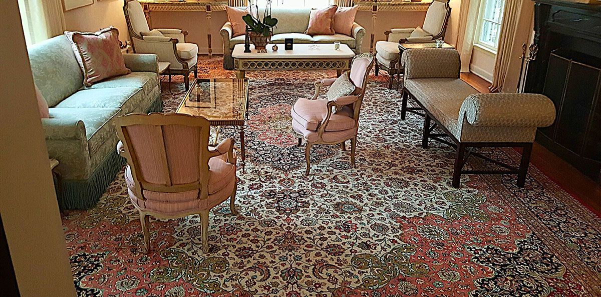 A living room with light-colored furniture, pink accent chairs, and an ornate rug