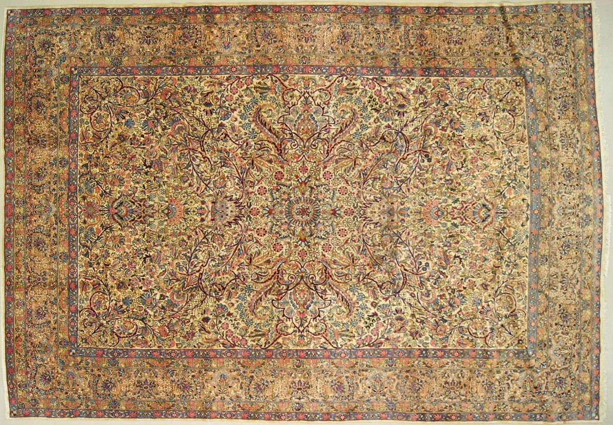 Overhead view of a rectangular, ornate rug with beige, brown, and red floral patterns