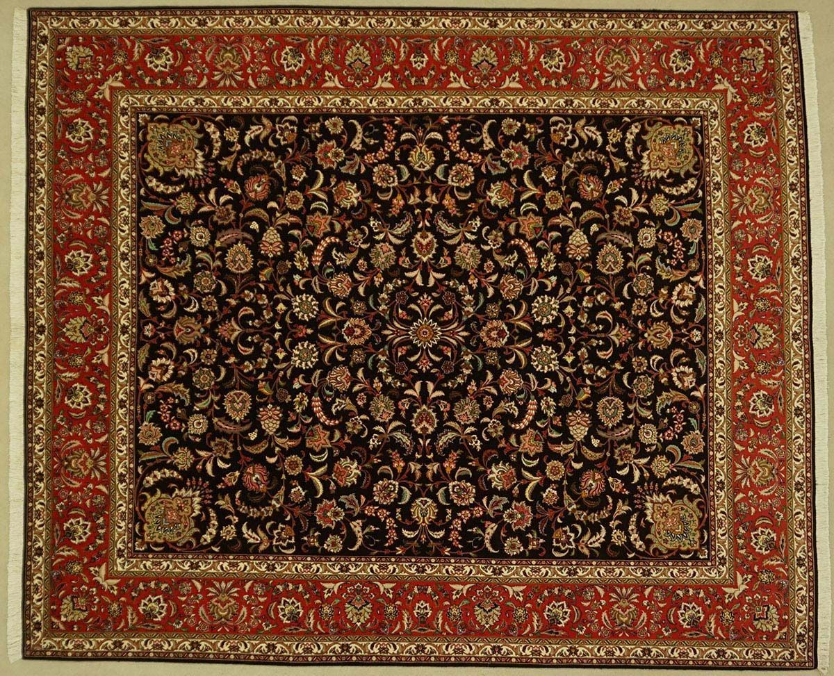 Red-bordered, floral patterned Oriental rug on a light-colored surface; the central design is primarily dark with floral patterns