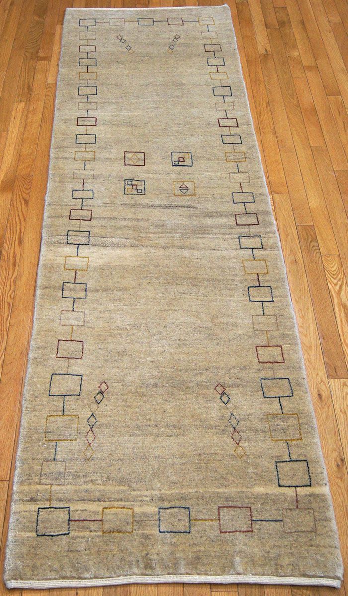 Beige rectangular rug with a linear black geometric pattern on a wooden floor