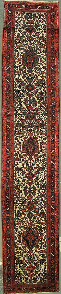 Narrow rectangular rug, red border, central floral design in beige, dark red, and green