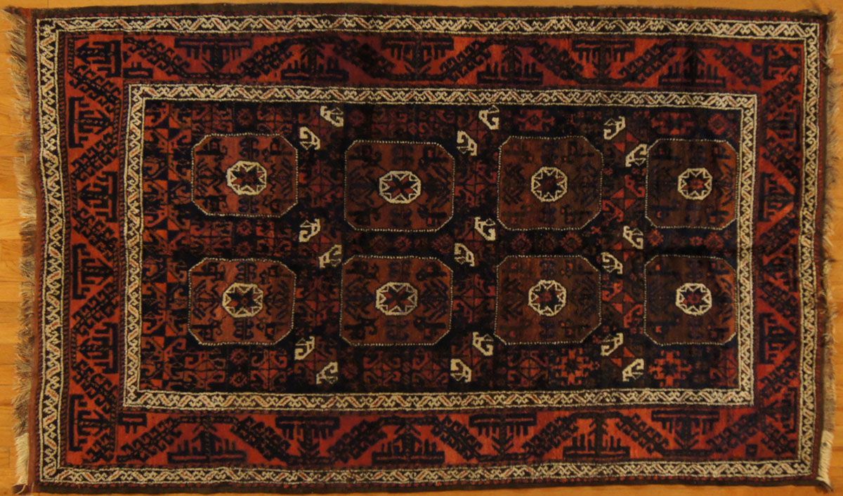 Red and brown patterned oriental rug with geometric shapes on a light wood floor