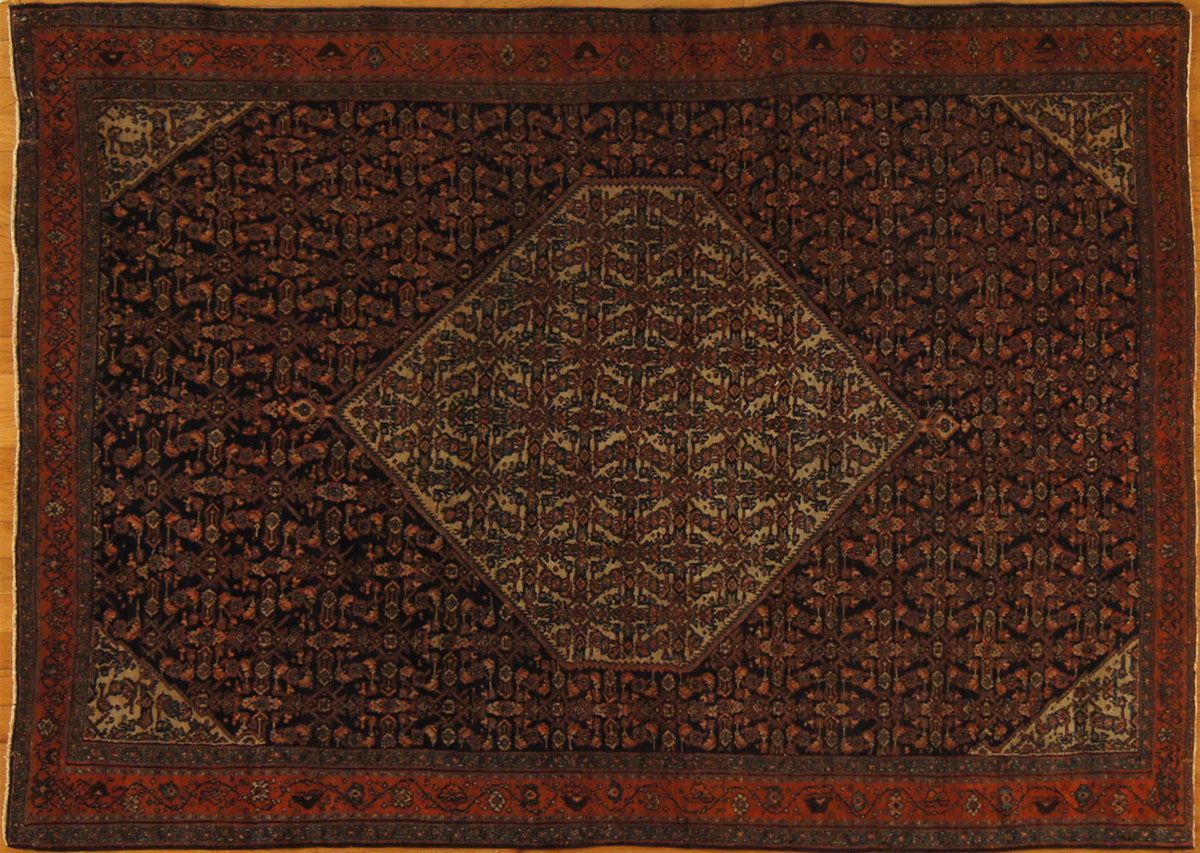Dark red Oriental rug with central diamond design and corner details on wooden floor
