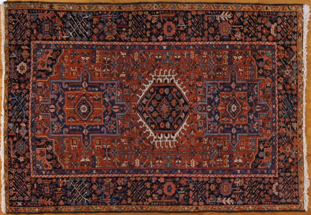 Oriental rug with a red and blue central pattern, dark blue border, and white fringe