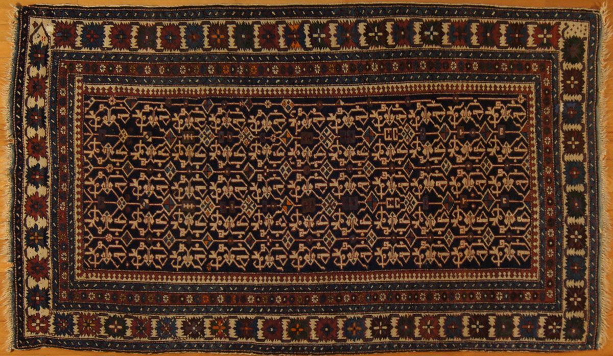 Dark blue and burgundy patterned rug on a light wooden surface, with rectangular border design