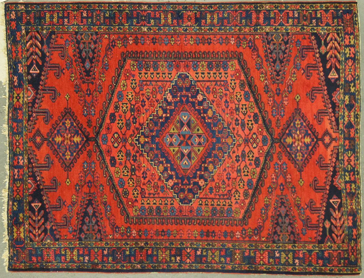 Red and blue oriental rug with a central hexagonal medallion and diamond accents