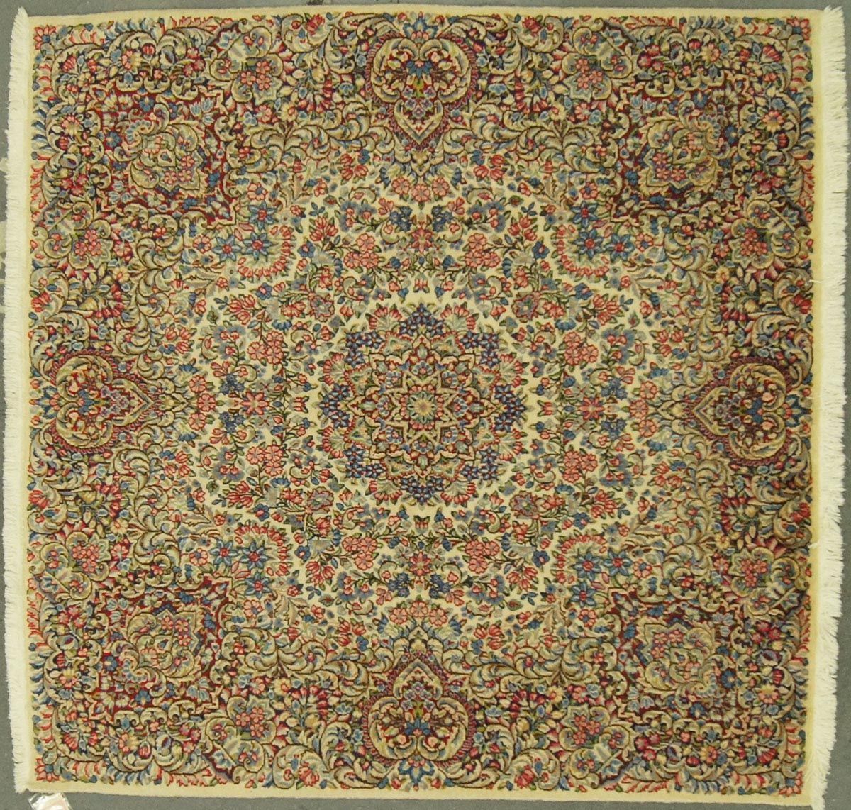 Intricately patterned rug with floral and geometric designs in muted reds, blues, and creams