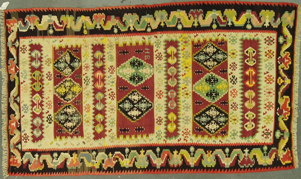 Rectangular, patterned rug with red, black, yellow, and green geometric designs