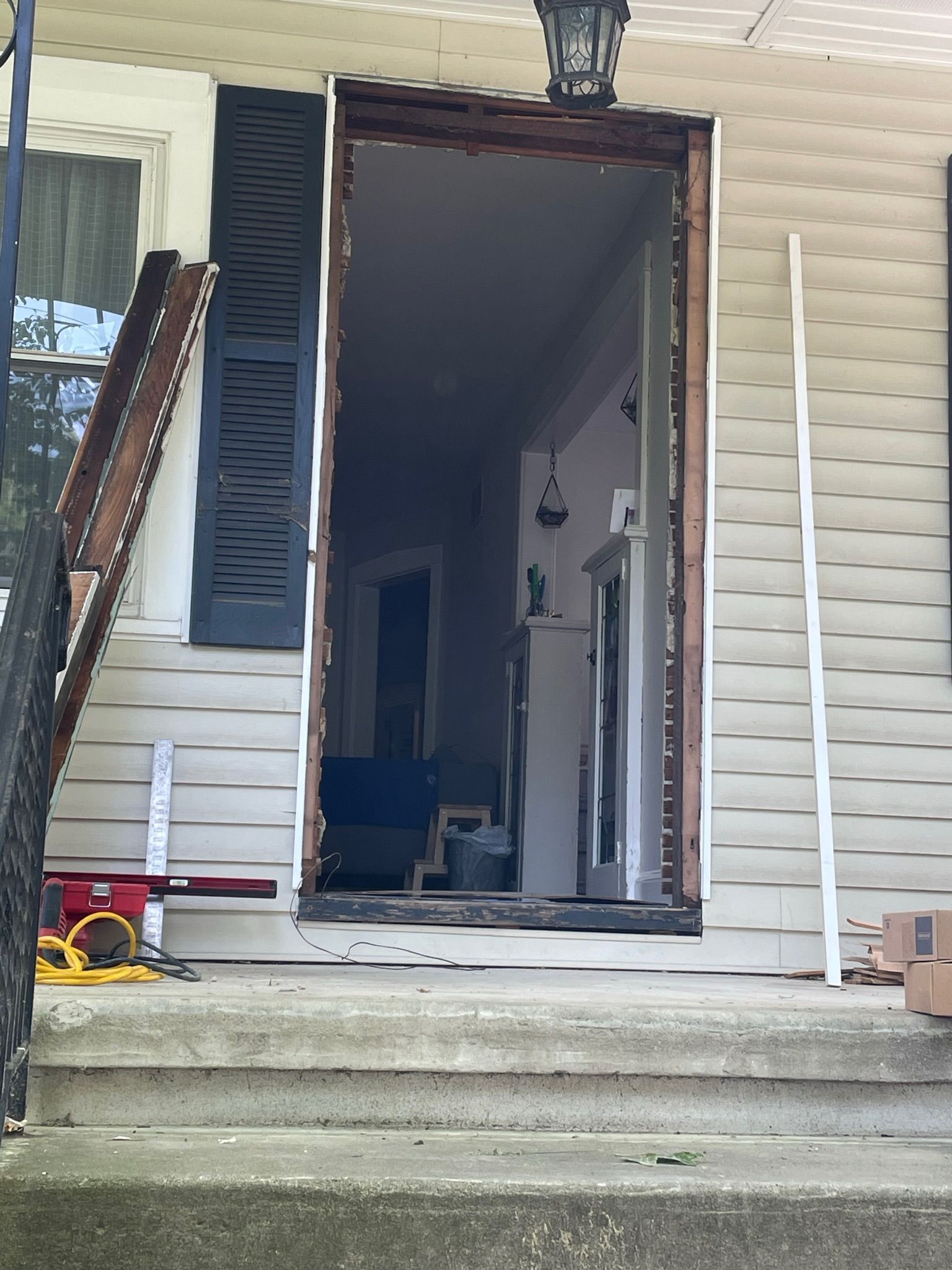 Exterior doorway during renovation; wood frame, exposed interior, white siding, black shutters.