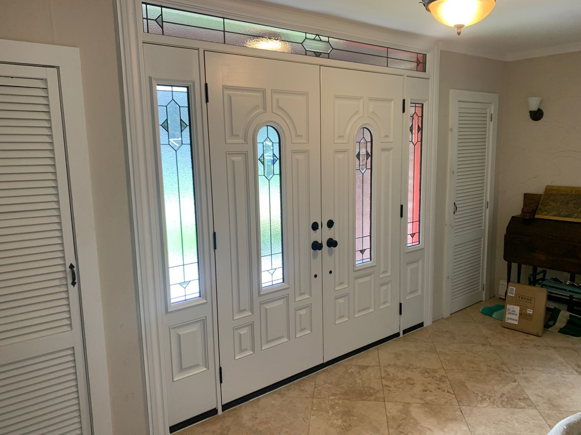 White front door with sidelights and transom window, inside a home.