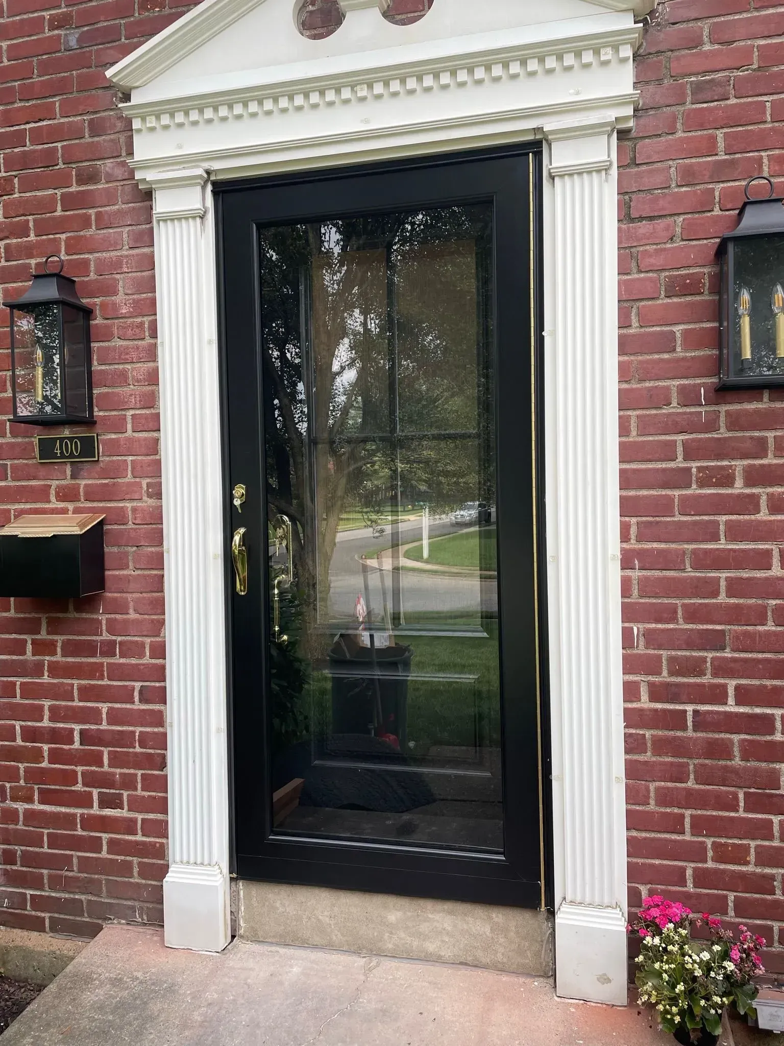 Black front door with glass panels and white trim on a red brick house.
