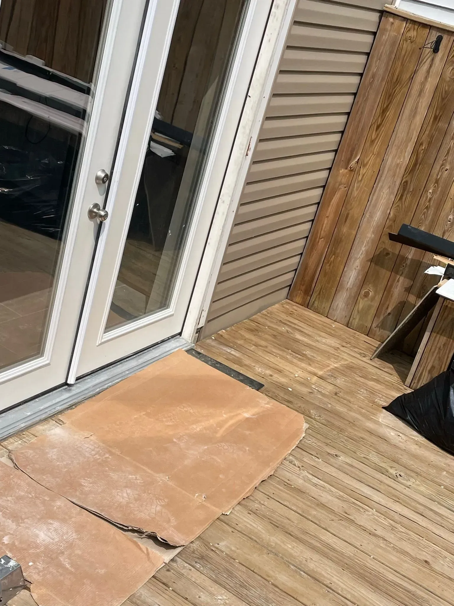 French doors opening onto a wooden deck, cardboard on the floor.