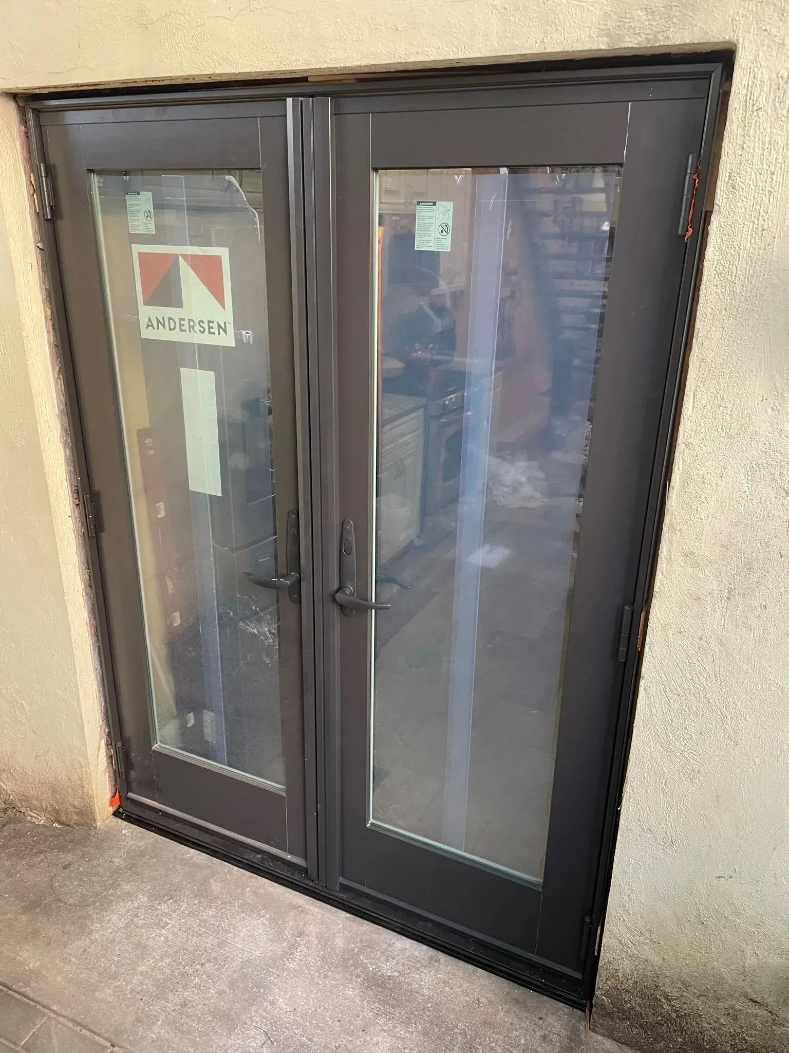 Black double doors with glass panels and a concrete exterior.