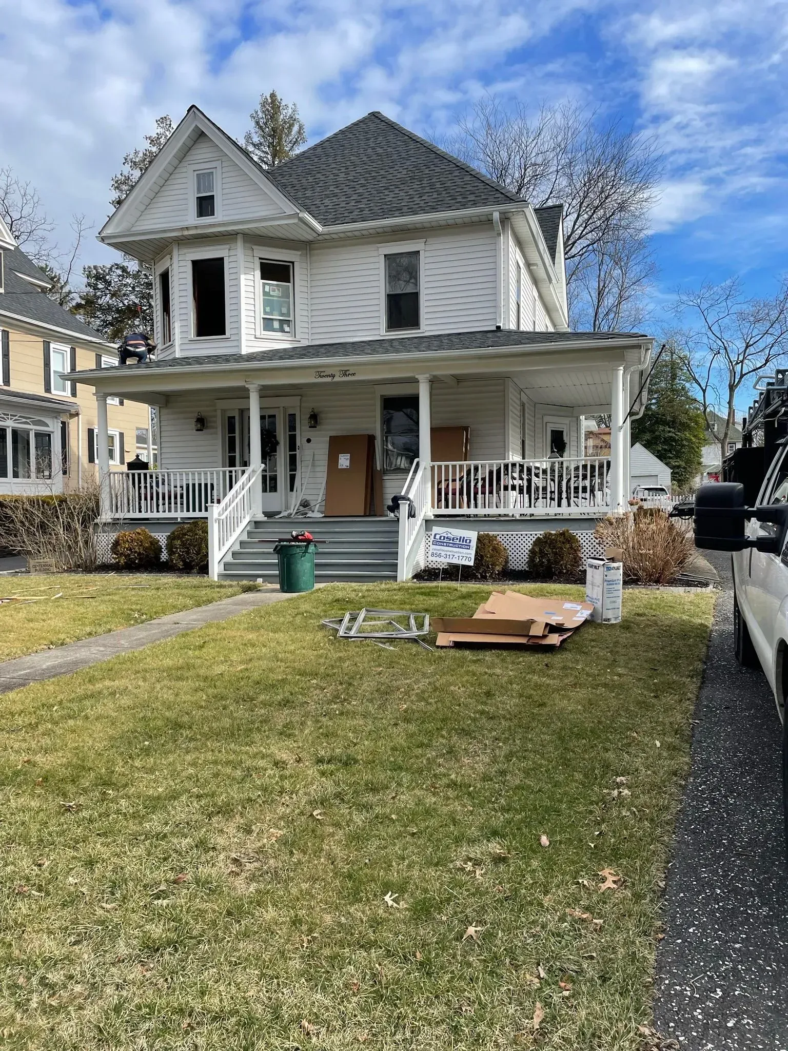 Two-story white house with porch, moving boxes, and grass lawn.