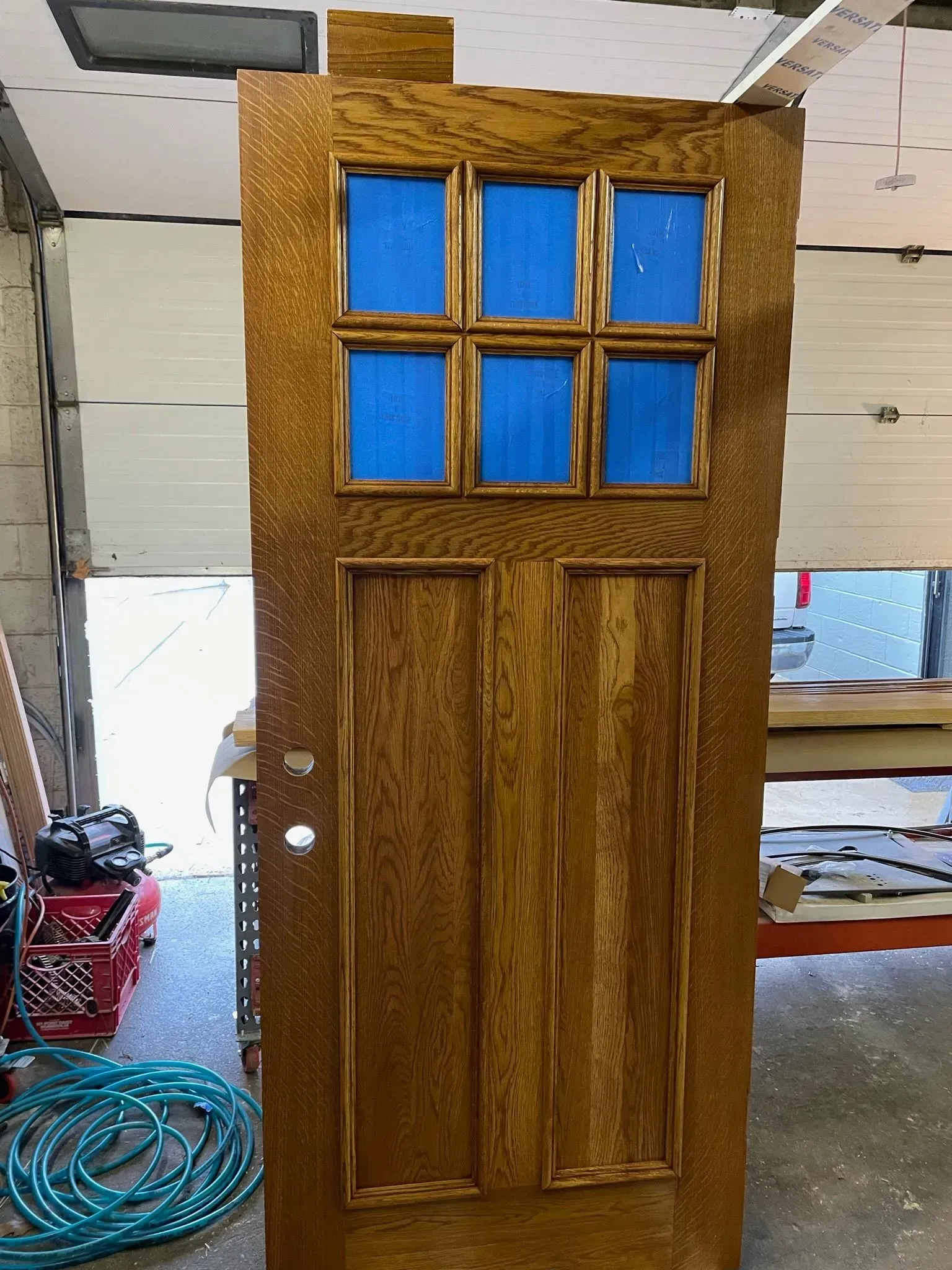 Wooden door with six small blue-filled window panes and two lower panels.