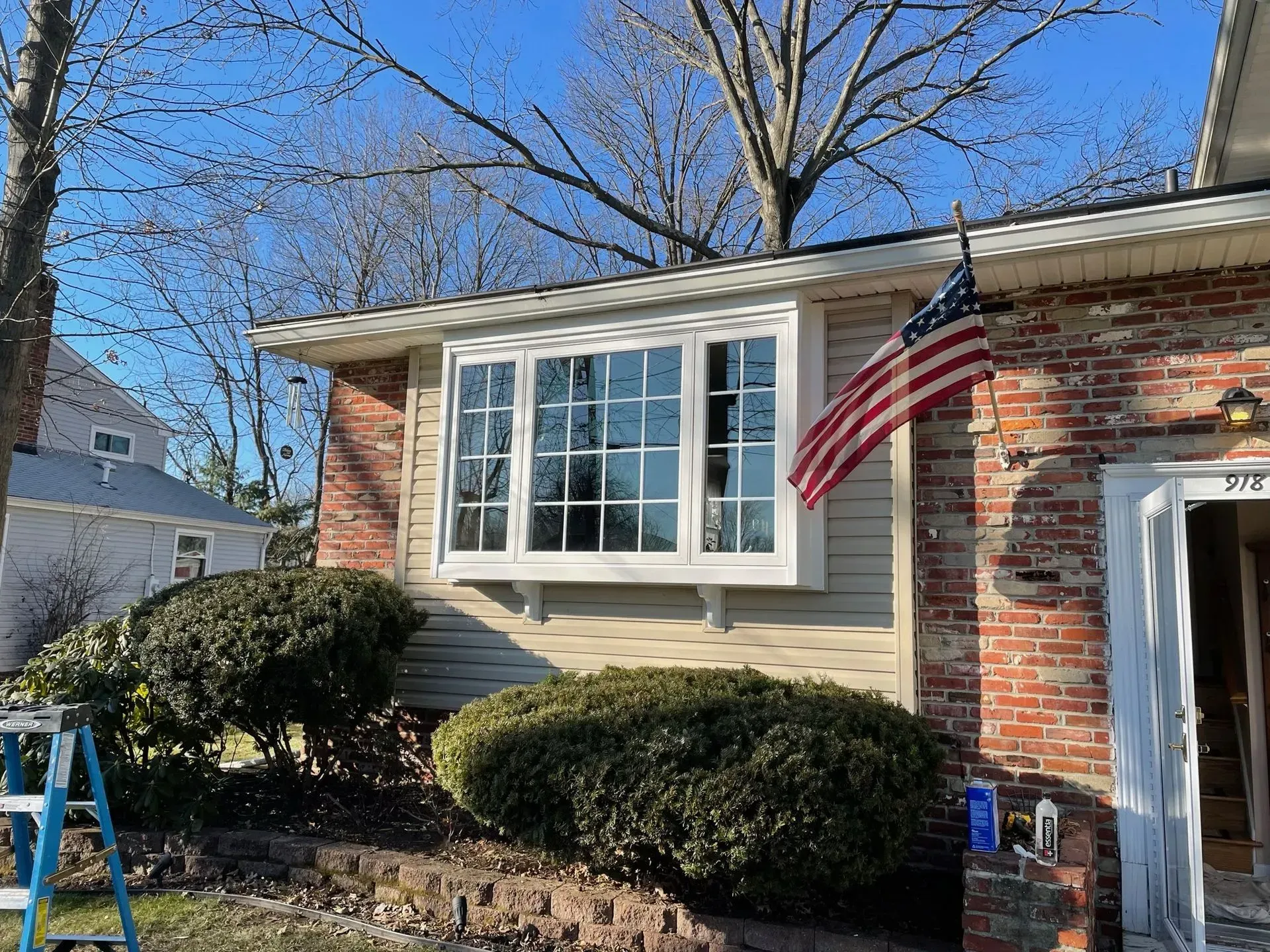 A house with a bay window and American flag on a sunny day.