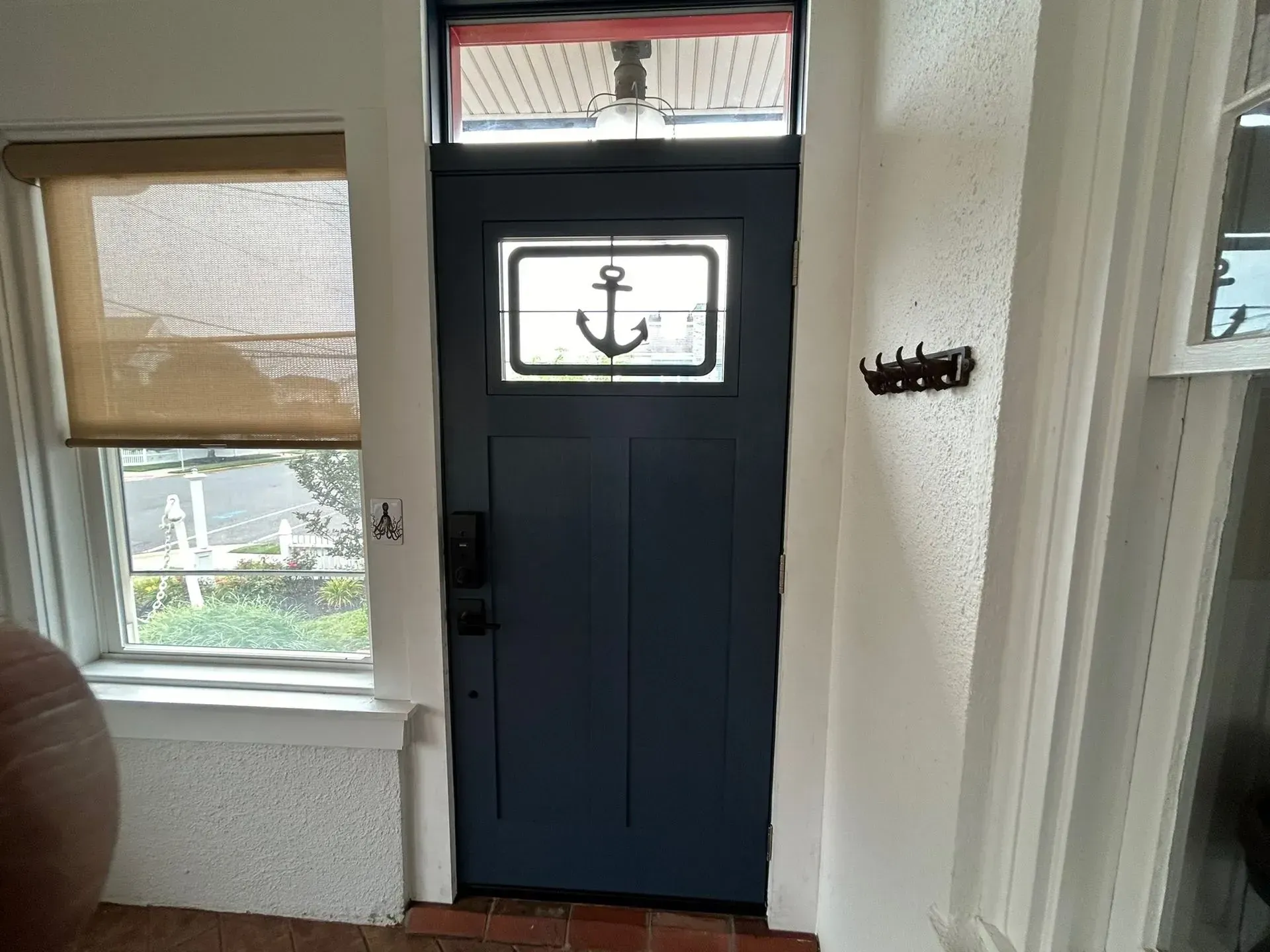 Blue front door with anchor design, window, and a hanging coat rack.