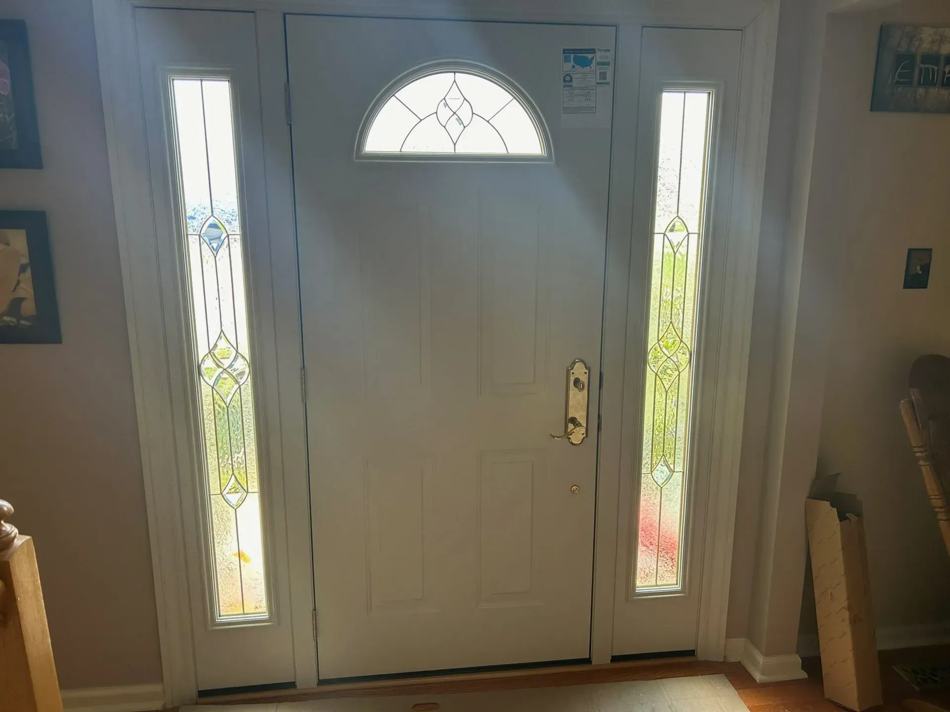 White front door with sidelights, featuring decorative glass.
