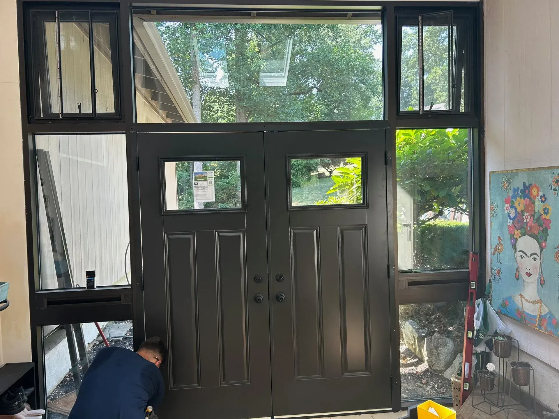 Black double doors with windows, person working, outdoor view.