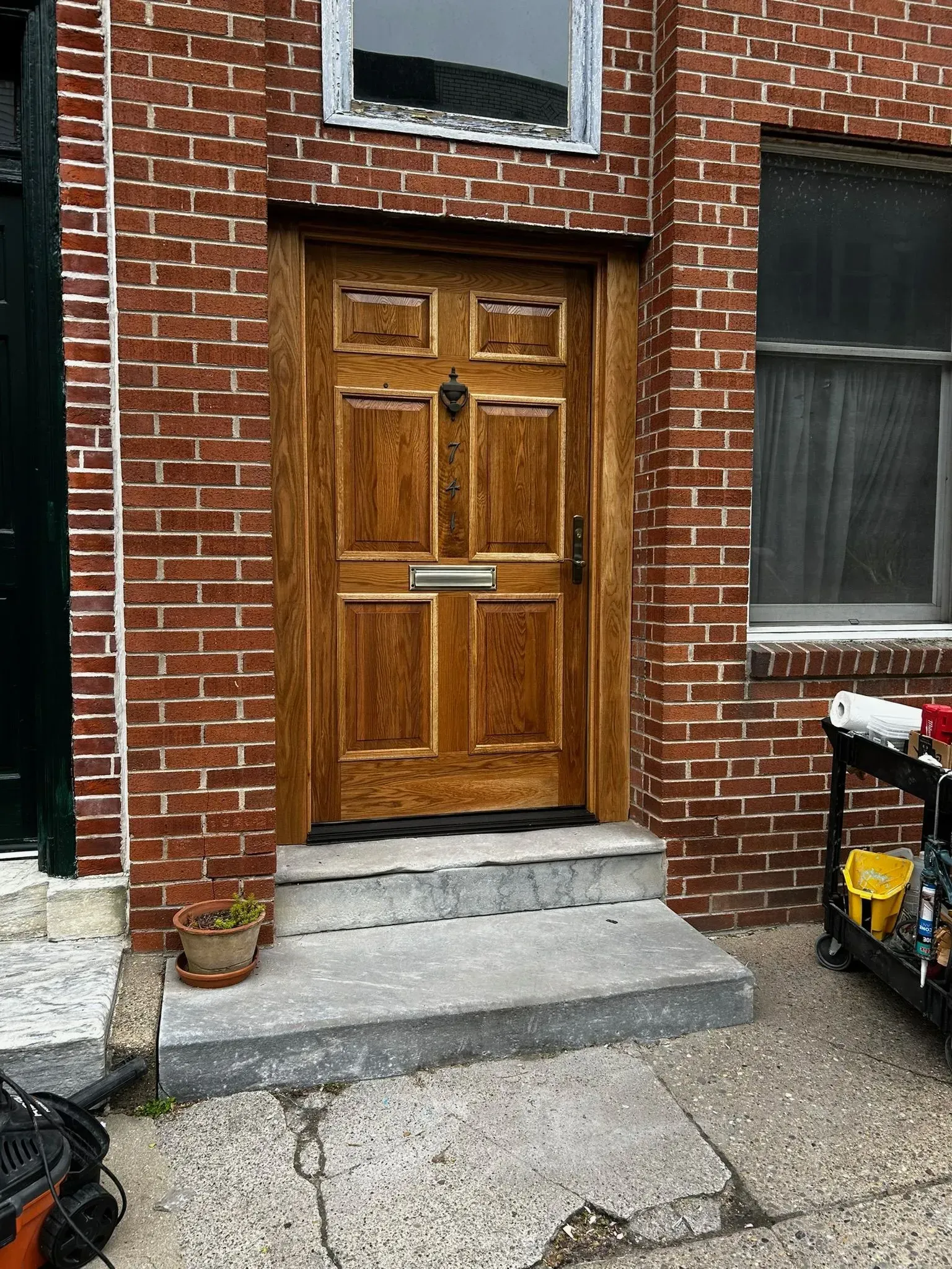 Wooden door in red brick building with concrete steps.