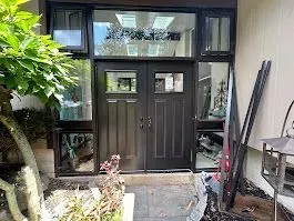 Black double doors with sidelights and transom window; an exterior entryway.