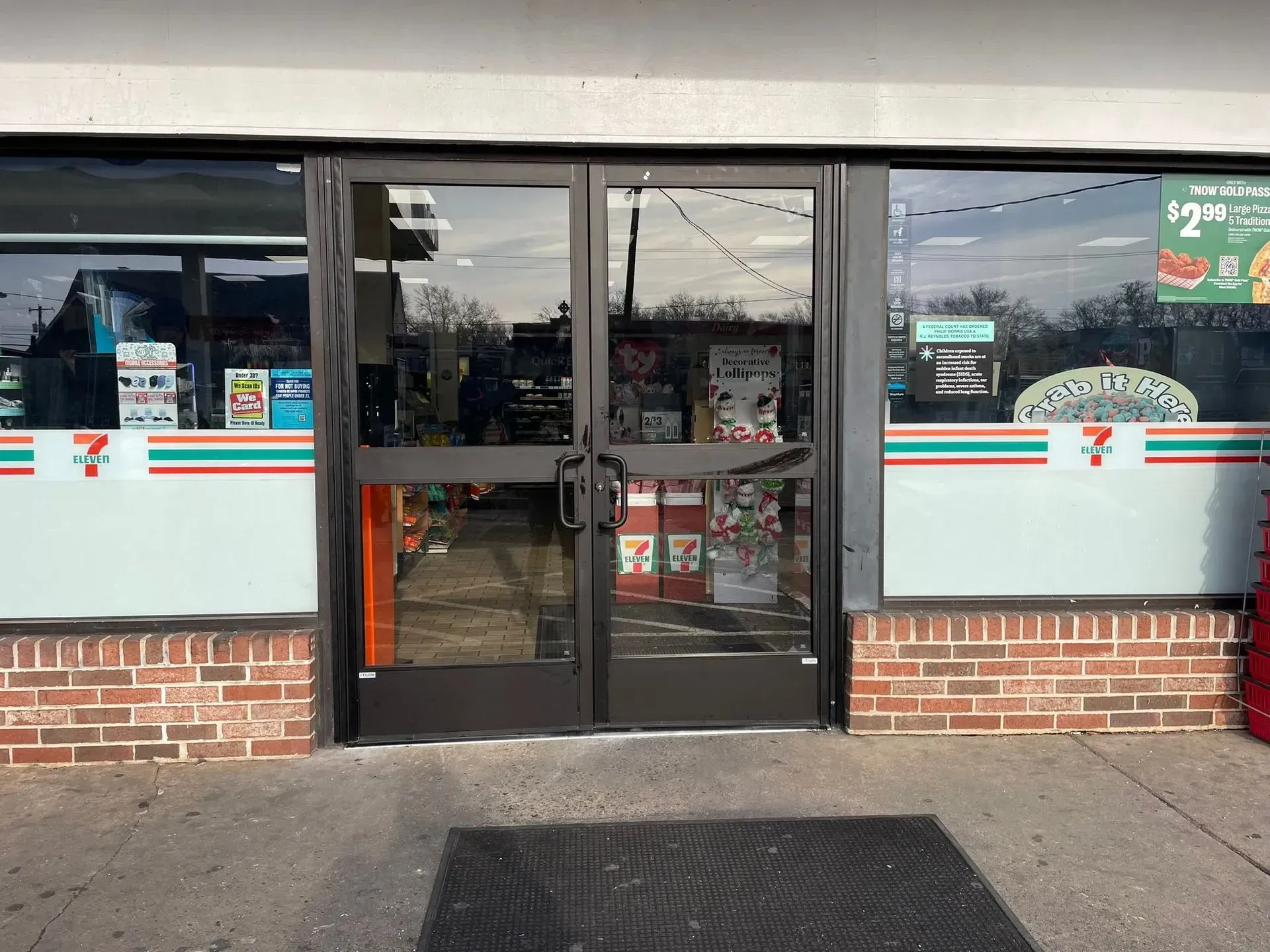 Exterior of a 7-Eleven store with glass doors, brick facade, and colorful signage.