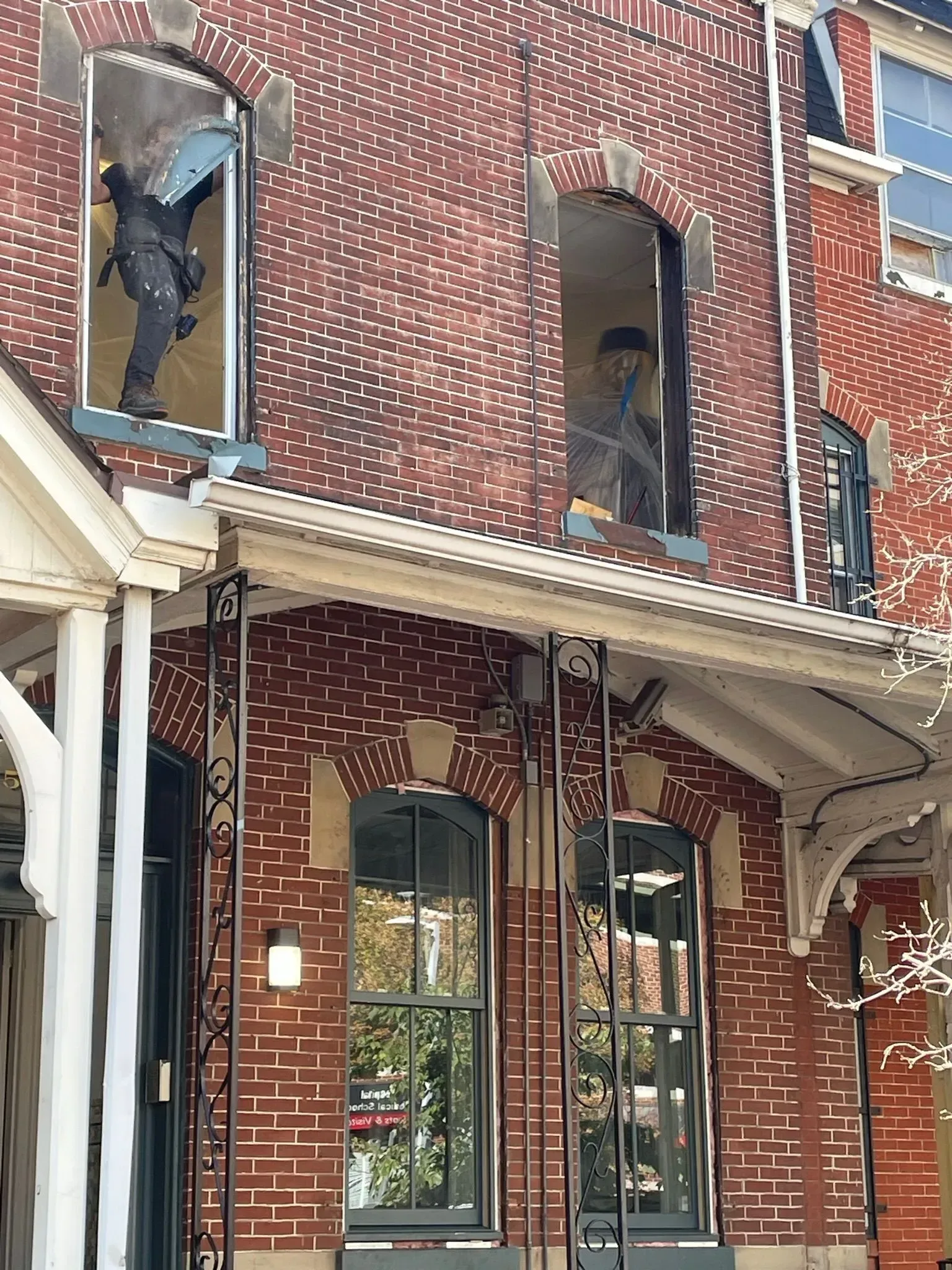 Two people working in upper story windows of a brick building.