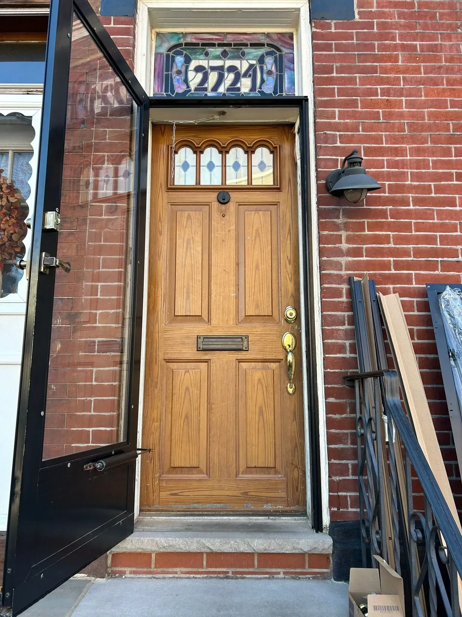 Wooden front door with storm door and stained glass above, red brick building, address 2721.