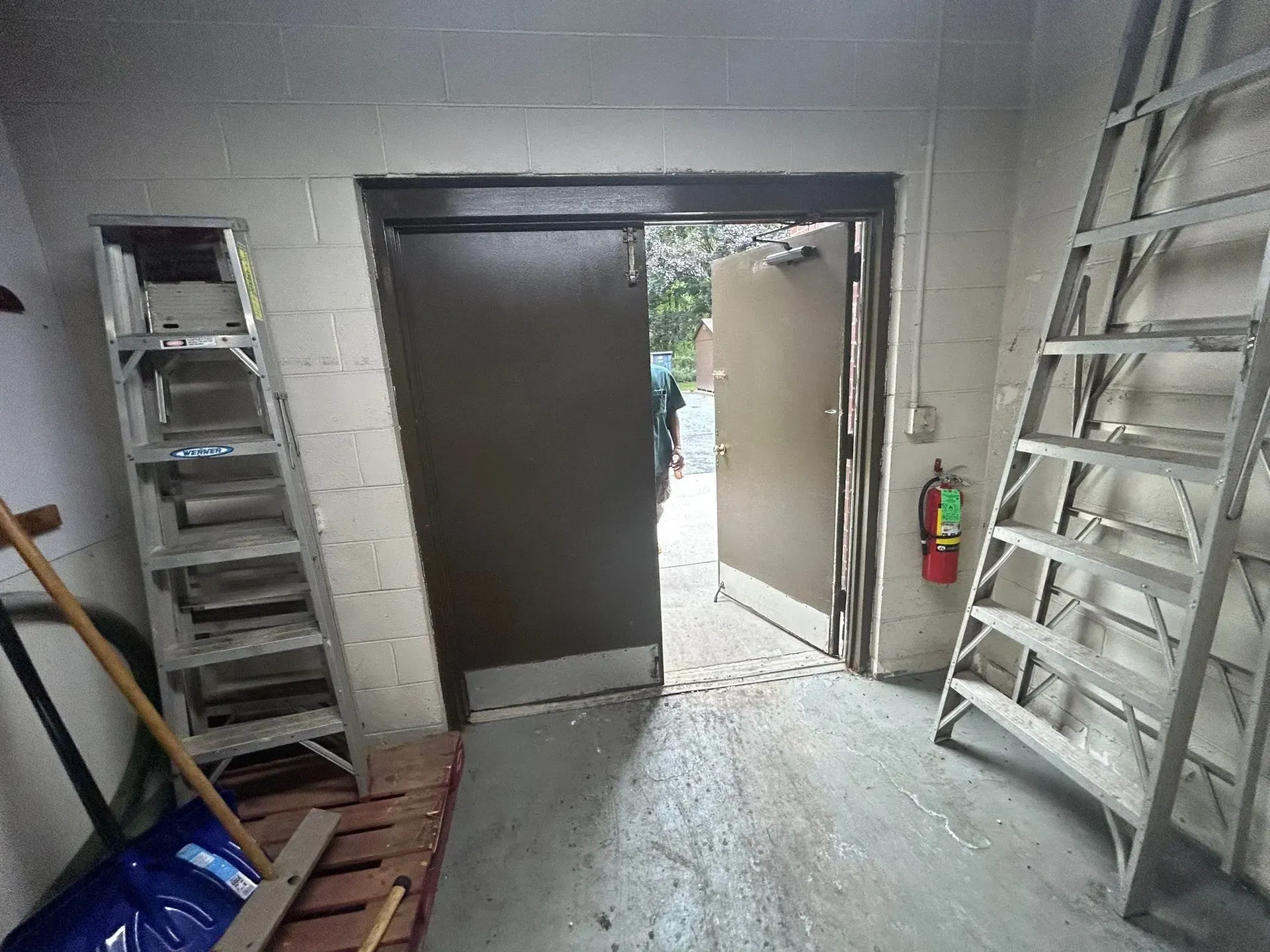 Doorway with open door, ladders on either side, and fire extinguisher.