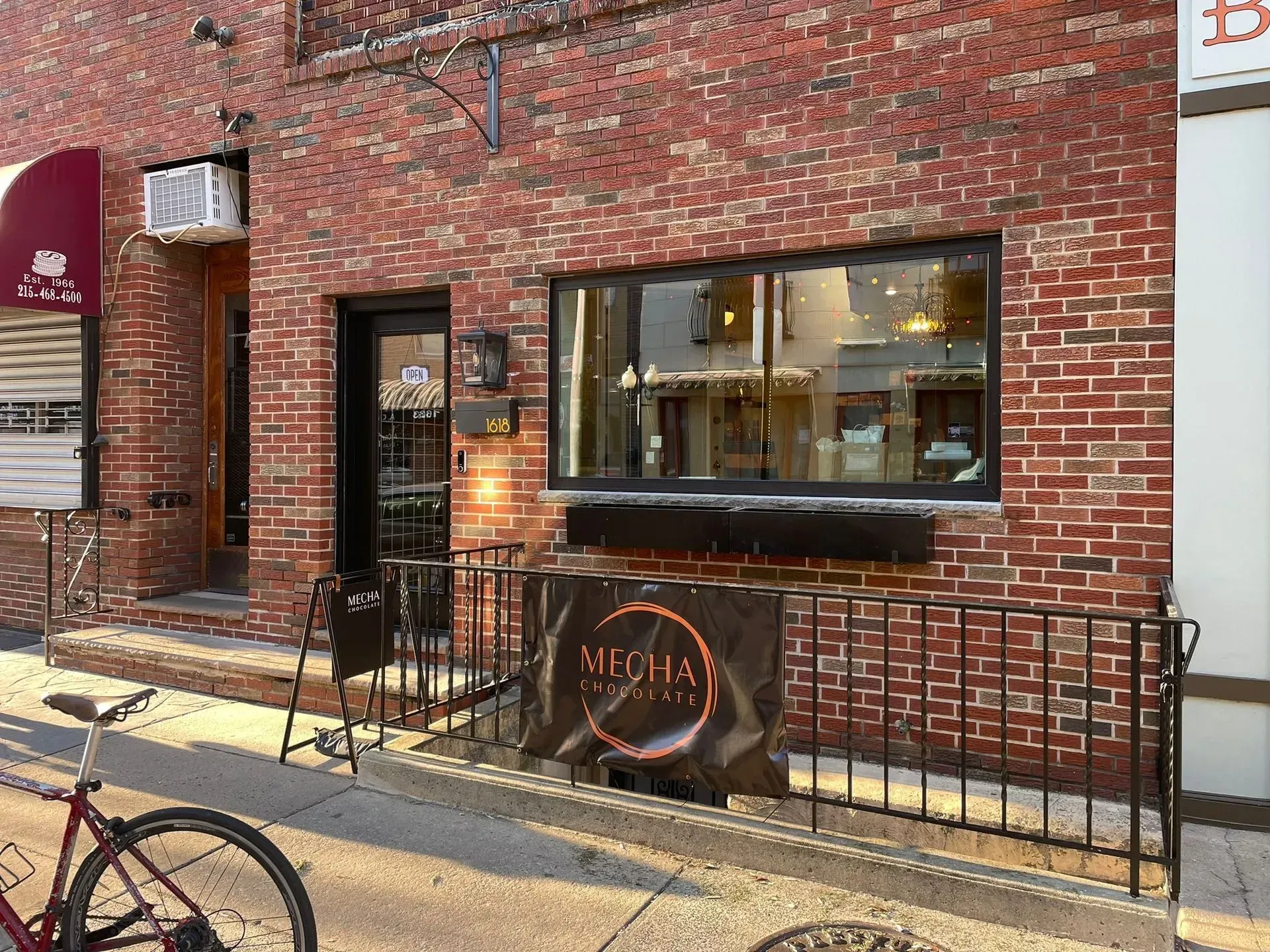 Exterior of Mecha restaurant, brick building with sign and bike parked in front.