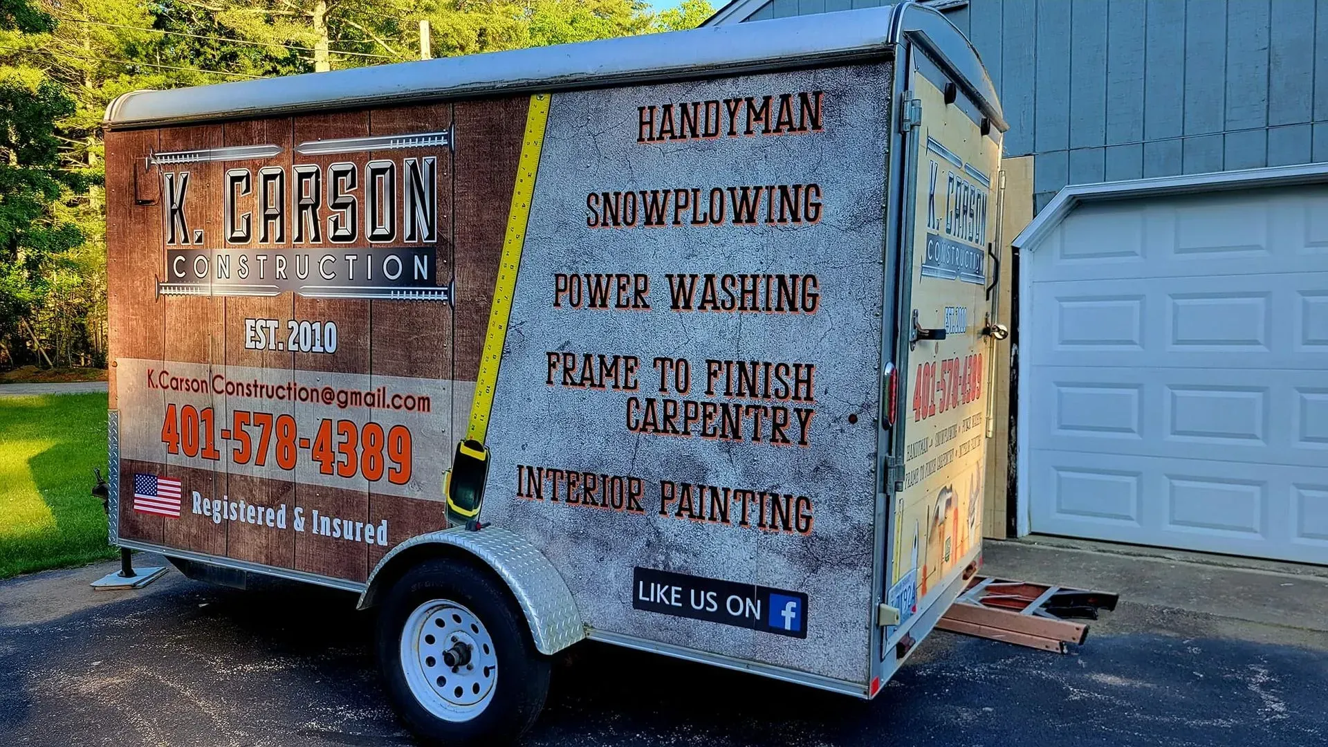 A trailer with the E. Carson Construction logo and services, including handyman, snow plowing, and finish carpentry.
