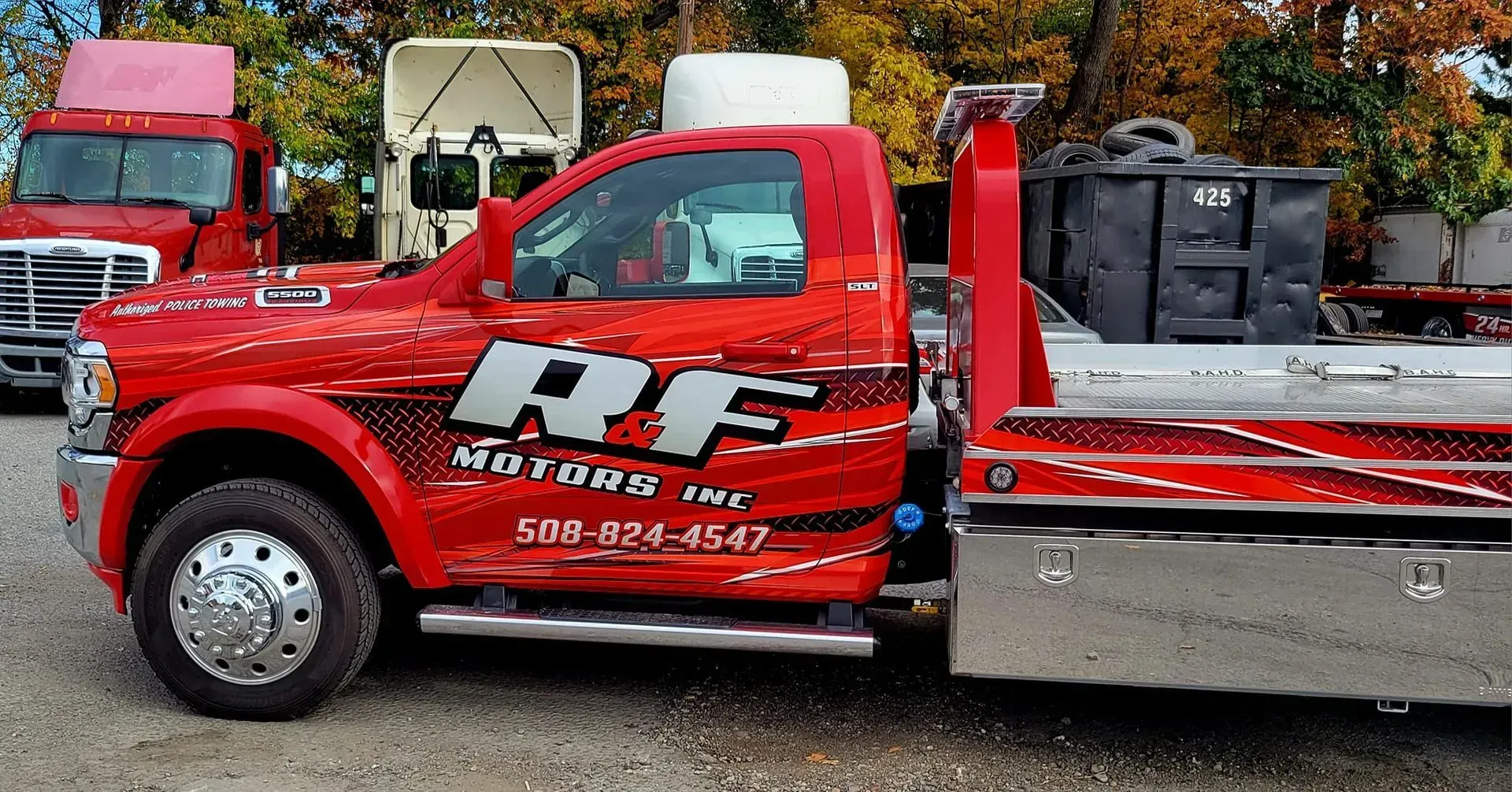Red tow truck with RF logo and phone number, parked outside.