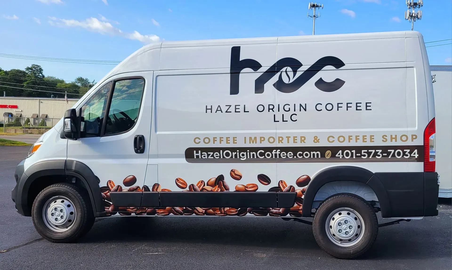 White van with Hazel Origin Coffee logo and coffee bean graphic parked outside.