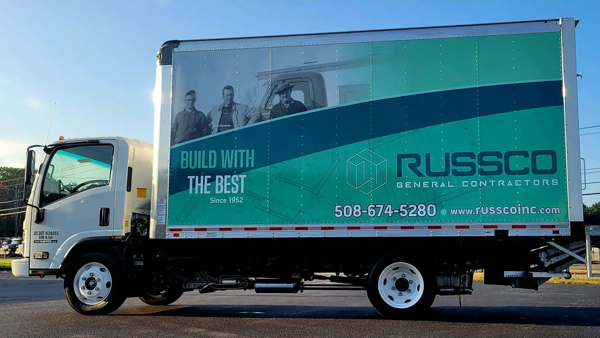 White truck with green and blue company logo; men in background; 
