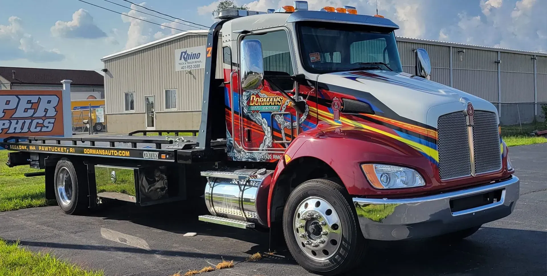 Tow truck with custom graphics parked on asphalt.