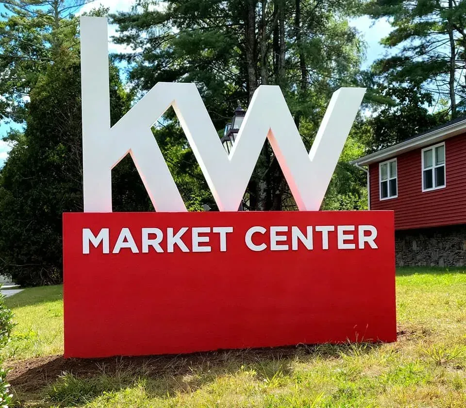 Large red and white Keller Williams Market Center sign outdoors.