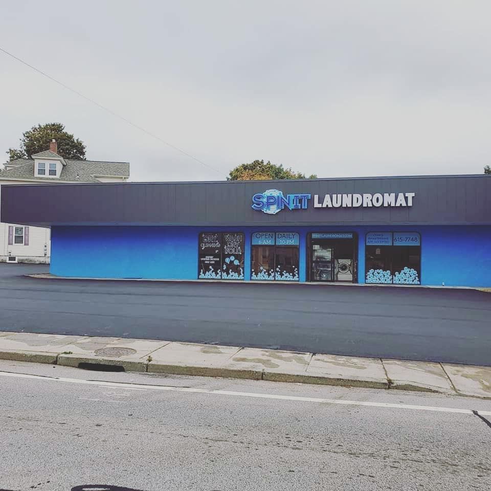 Exterior view of a laundromat with blue and black facade. Sign reads 