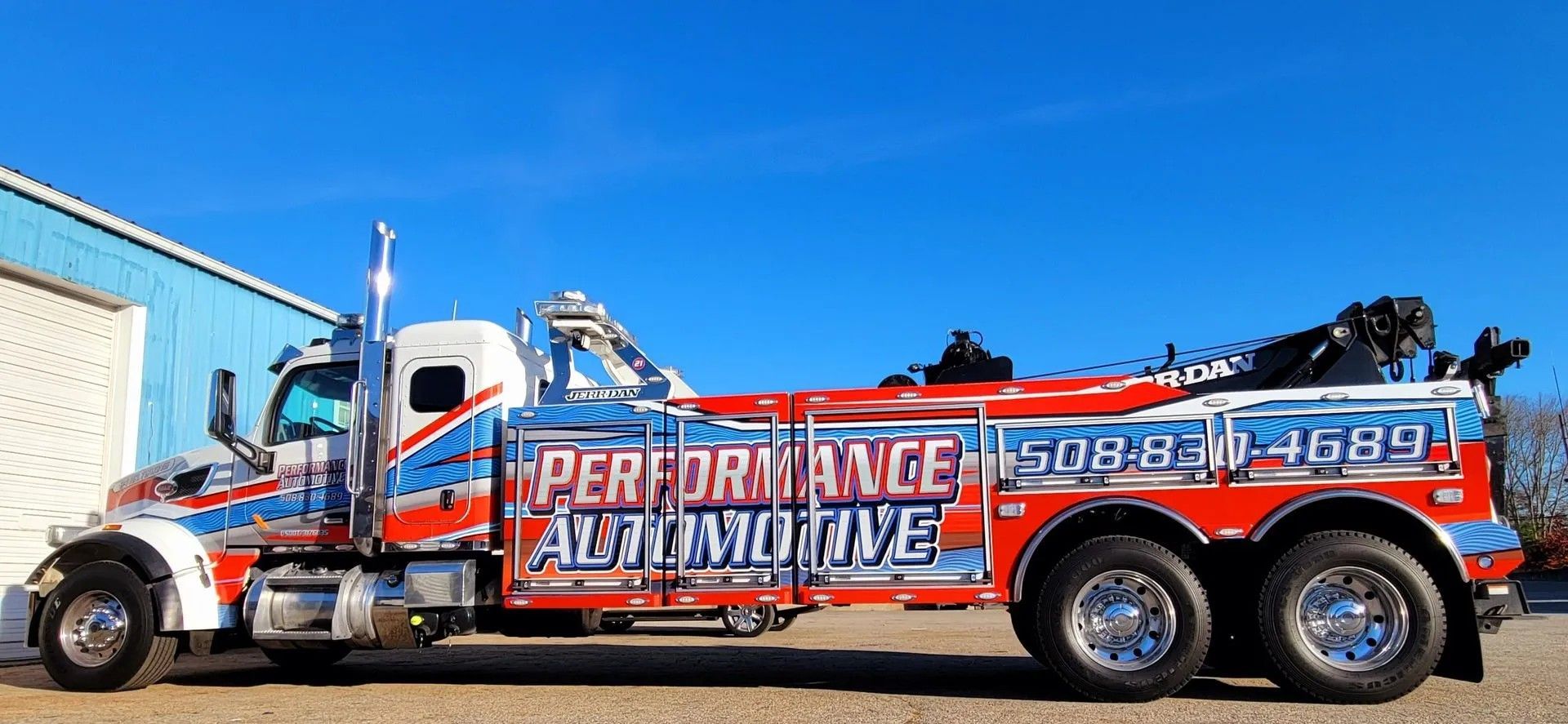 A tow truck with red, blue, and white graphics, advertising