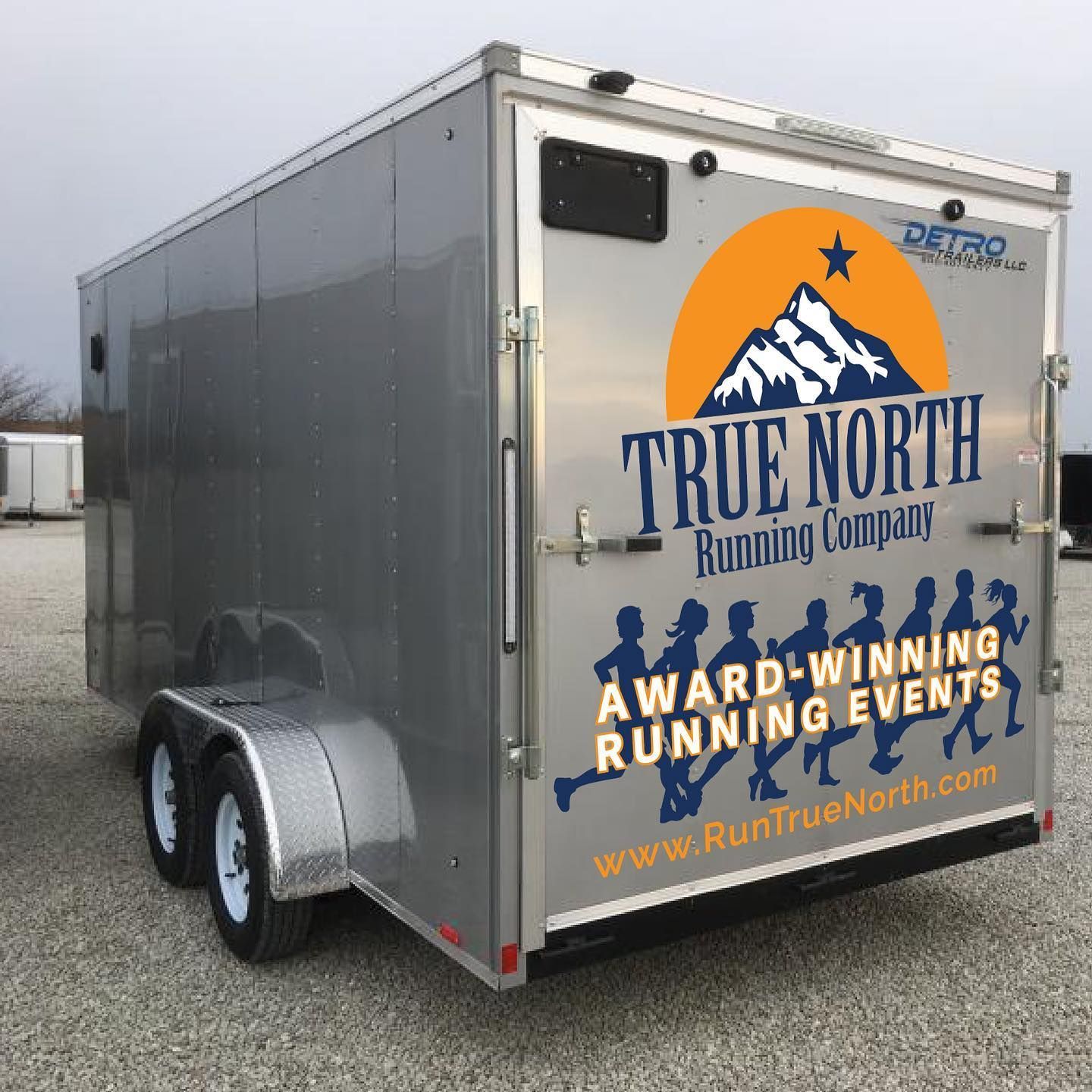 Gray trailer with True North Running Company logo: mountain, people, award-winning running events.