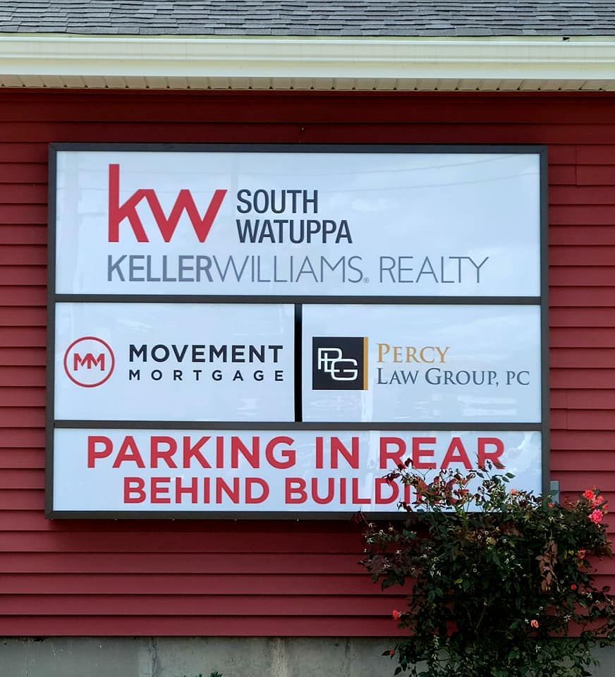 Sign for Keller Williams Realty and other businesses. Red and white with directions to parking in the rear.
